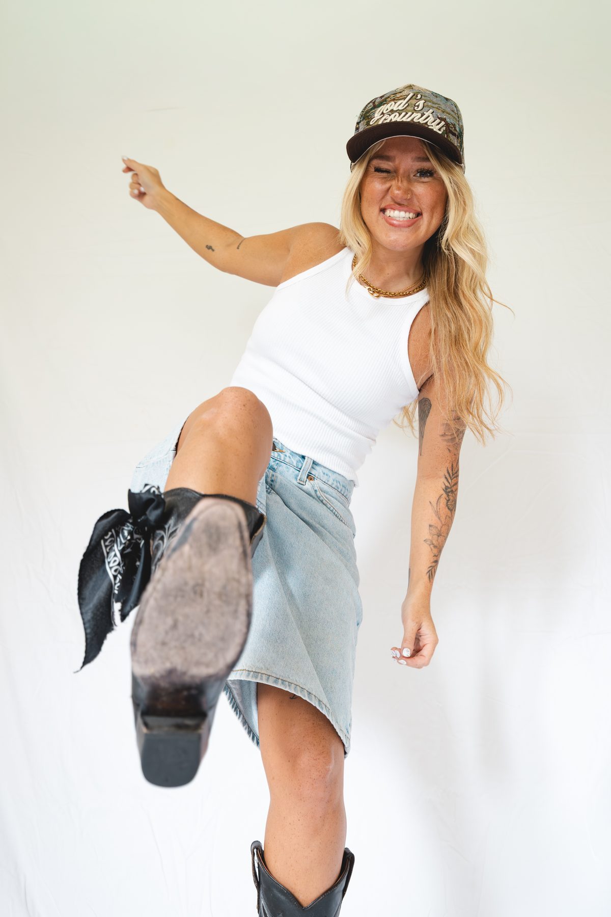 Chloe Wilson pointing at the camera, wearing a camo hat and cowboy boots